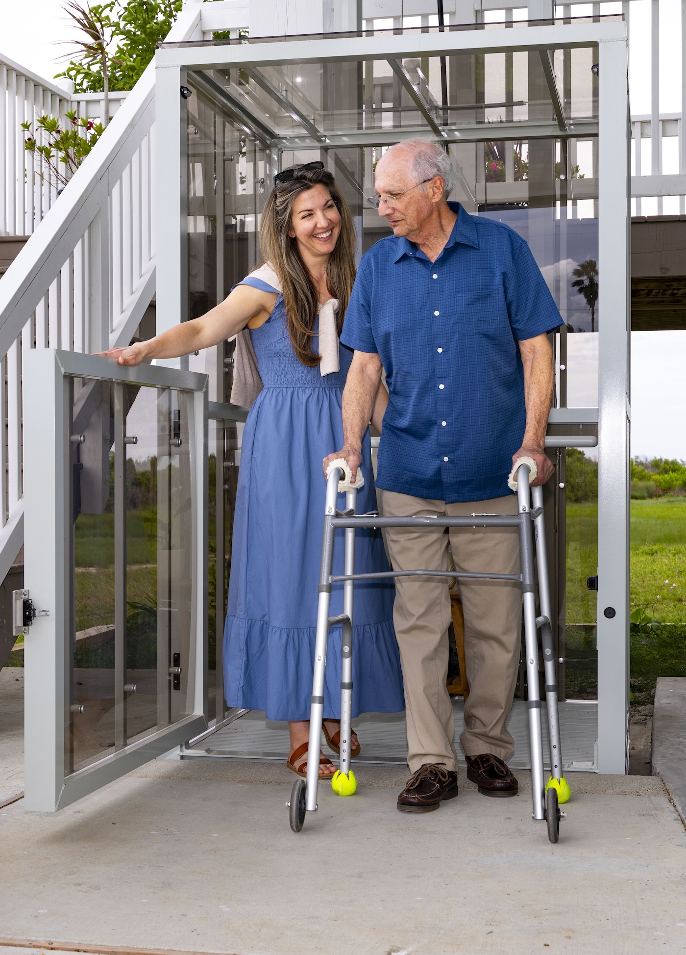 Women holding the lift gate open and an old man using the walker to walk out